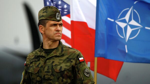 A Polish soldier stands near US and Poland's national flags and a NATO flag in Swidwin, northern west Poland, April 23, 2014 - Sputnik Türkiye