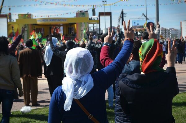 Nevruz Alanı'nda toplananlar, Kürt Ulusal Marşı ‘Ey Raqip'i söyleyerek ‘abluka'daki ilçelerde hayatlarını kaybedenler için ‘saygı duruşu'nda bulundu. - Sputnik Türkiye