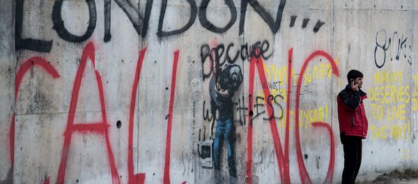 Sığınmacıların İngiltere'ye geçebilmek için bekledikleri Fransa'nın Calais kentindeki 'Jungle' isimli kampta telefonla konuşan bir adam. - Sputnik Türkiye
