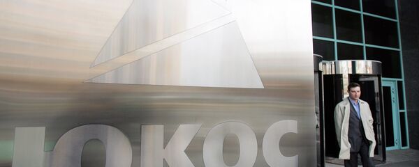 A man passes by a Yukos logo at the headquarters of the oil company in Moscow after the latest auction for the sale of package of assets the stricken giant, 04 April 2007 - Sputnik Türkiye