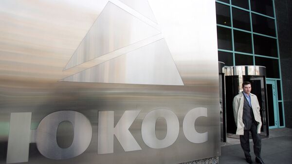A man passes by a Yukos logo at the headquarters of the oil company in Moscow after the latest auction for the sale of package of assets the stricken giant, 04 April 2007 - Sputnik Türkiye