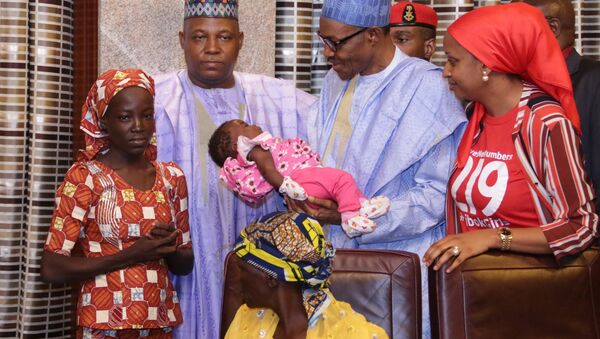 Nijerya Devlet Başkanı Buhari, Boko Haram'dan kurtarılan ilk 'Çibok kızının' bebeğini kucağına aldı. - Sputnik Türkiye