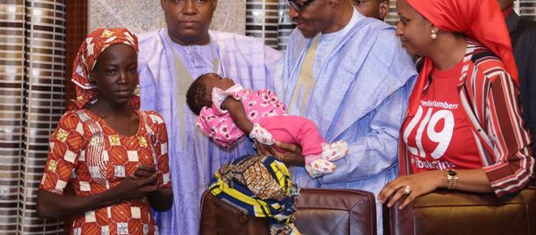 Nijerya Devlet Başkanı Buhari, Boko Haram'dan kurtarılan ilk 'Çibok kızının' bebeğini kucağına aldı. - Sputnik Türkiye