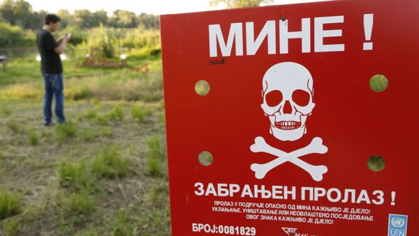 A Bosnian man plays the Pokemon game on his phone as he stands near a sign warning of a Minefield, near the Bosnian town of Brcko, on Tuesday, July 19, 2016 - Sputnik Türkiye
