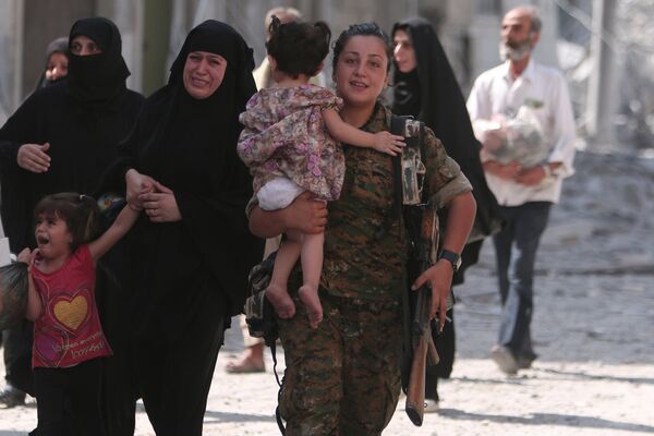 Gözü yaşlı Menbiçli kadınlara yardım eden Demokratik Suriye Güçleri askeri. - Sputnik Türkiye