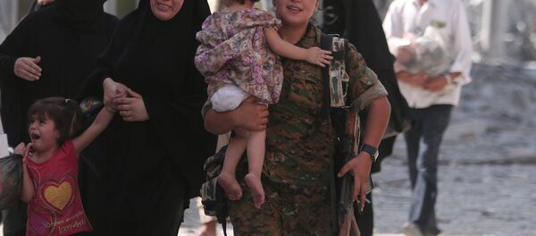 Gözü yaşlı Menbiçli kadınlara yardım eden Demokratik Suriye Güçleri askeri. - Sputnik Türkiye