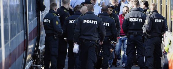 Danish police guards a train with migrants, mainly from Syria and Iraq, at Rodby railway station, southern Denmark - Sputnik Türkiye