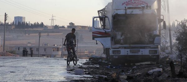 A boy rides a bicycle near a damaged aid truck after an airstrike on the rebel held Urm al-Kubra town, western Aleppo city, Syria September 20, 2016. - Sputnik Türkiye