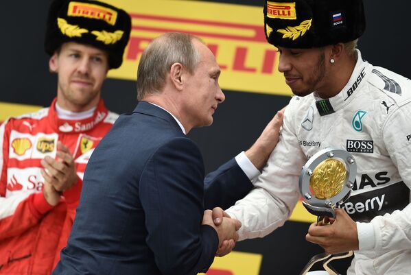 Rusya Devlet Başkanı Vladimir Putin, Formula 1 Soçi Grand Prix'de birinciliği elde eden Mercedes pilotu Lewis Hamilton’a kKupasını takdim ediyor. - Sputnik Türkiye