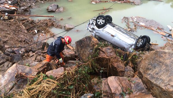 A rescue worker is seen next to an overturned car at the site of a landslide caused by heavy rains brought by Typhoon Megi, in Sucun Village, Lishui, Zhejiang province, China, September 29, 2016 - Sputnik Türkiye