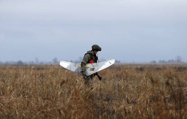 Tatbikata katılan bir asker insansız hava aracını (İHA) taşıyor. - Sputnik Türkiye
