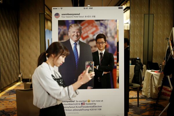 Güney Kore'nin başkenti Seul'deki bir otelde genç bir kadın Trump'ın fotoğrafı ile kendi resmini çekiyor. - Sputnik Türkiye