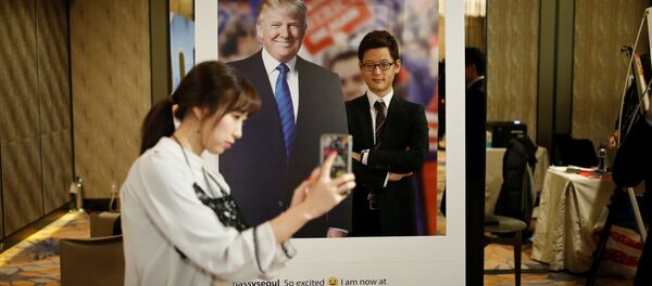 Güney Kore'nin başkenti Seul'deki bir otelde genç bir kadın Trump'ın fotoğrafı ile kendi resmini çekiyor. - Sputnik Türkiye
