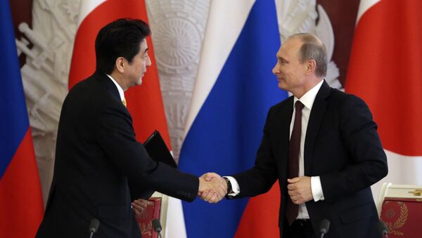 Japanese Prime Minister Shinzo Abe (L) shakes hands with Russian President Vladimir Putin - Sputnik Türkiye