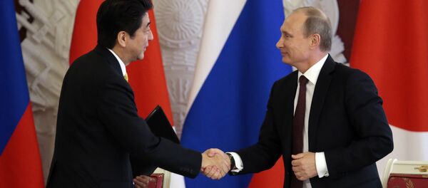 Japanese Prime Minister Shinzo Abe (L) shakes hands with Russian President Vladimir Putin - Sputnik Türkiye