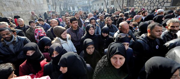 Halep'te kentin doğu kesiminden tahliye edilen akrabalarını ziyaret için bir polis merkezinin önünde bekleyen siviller - Sputnik Türkiye