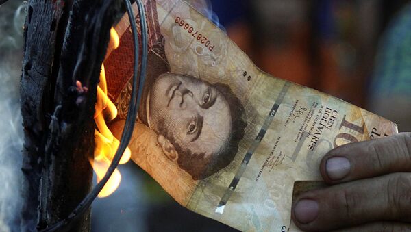 Ekonomik krizi protesto eden bir Venezüellalı eylemci 100 bolivarlık banknotu yakıyor - Sputnik Türkiye