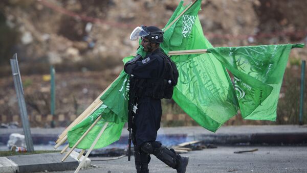 A member of the Israeli security forces carries flags of the Palestinian movement Hamas. - Sputnik Türkiye