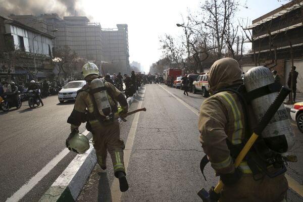 Tahran'ın merkezindeki  Plasku İş Merkezi'nde çıkan yangını söndürmeye çalışan itfaiyeci. - Sputnik Türkiye