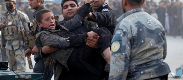 Afgan polisi Celalabad'daki bir bombalı saldırıda yaralanan çocuğu taşıyor - Sputnik Türkiye