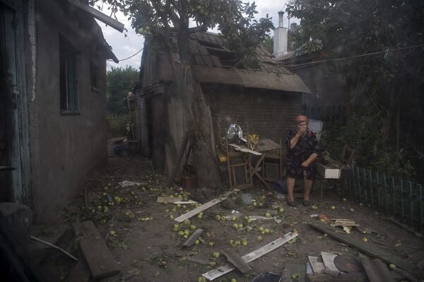 Lugansk sakini, Ukrayna ordusunun topçu saldırısında yıkılan evinin önünde duruyor. - Sputnik Türkiye