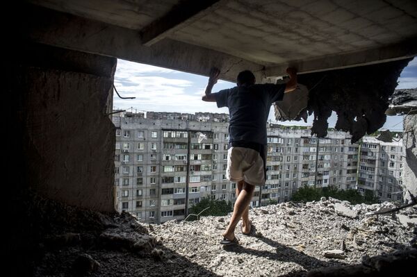 Lugansk’ın Mirniy mahallesine topçu saldırısının ardından bir adam binadaki hasarı inceliyor. - Sputnik Türkiye