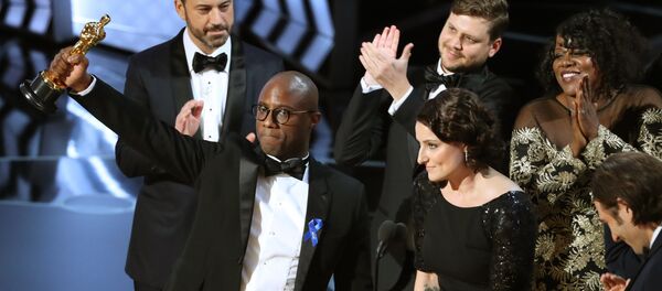 89th Academy Awards - Oscars Awards Show - Hollywood, California, U.S. - 26/02/17 - Writer and Director Barry Jenkins of Moonlight holds up the Best Picture Oscar in front of host Jimmy Kimmel (rear) as he stands with Producer Adele Romanski (R). - Sputnik Türkiye