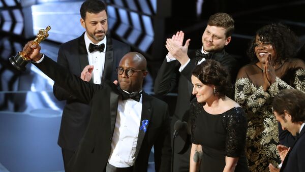 89th Academy Awards - Oscars Awards Show - Hollywood, California, U.S. - 26/02/17 - Writer and Director Barry Jenkins of Moonlight holds up the Best Picture Oscar in front of host Jimmy Kimmel (rear) as he stands with Producer Adele Romanski (R). - Sputnik Türkiye