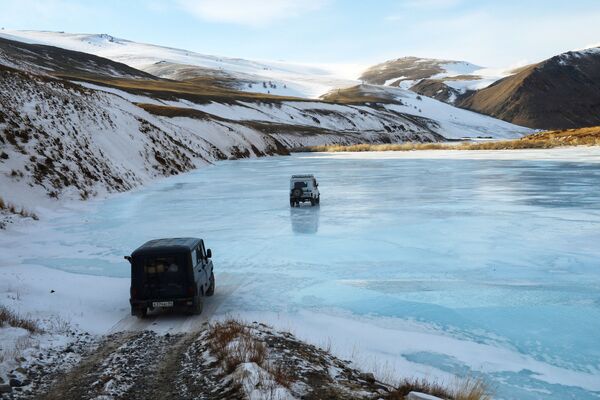 Rusya'nın Altay Cumhuriyeti'nde buz tutmuş nehirden geçen arabalar. - Sputnik Türkiye