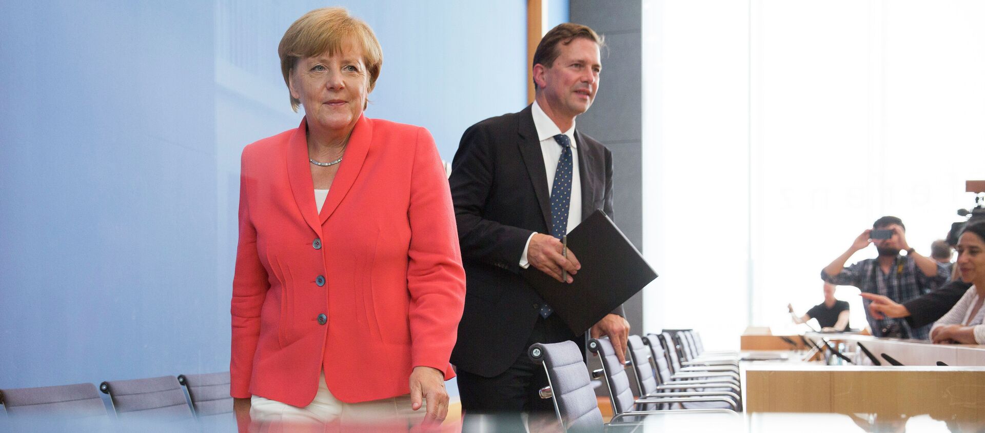 German Chancellor Angela Merkel, left, and government spokesman Steffen Seibert leave after Merkel's annual summer news conference in Berlin, Germany, Monday, Aug. 31, 2015 - Sputnik Türkiye, 1920, 06.03.2017