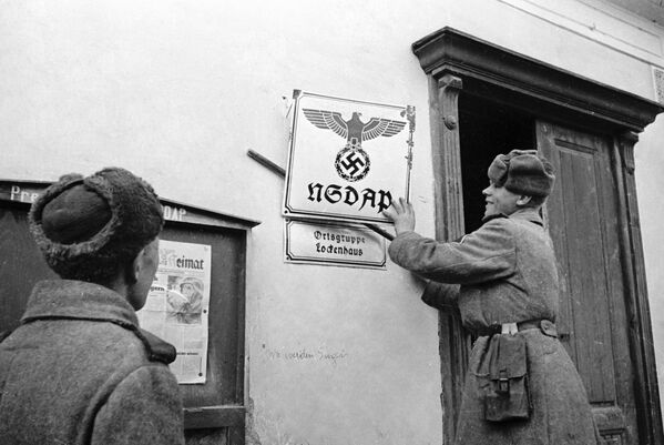 Avusturya’yı faşist güçlerden kurtaran Sovyet askerler, Lekengauz köyündeki binalardan Nazi tabelalarını söküyor. - Sputnik Türkiye