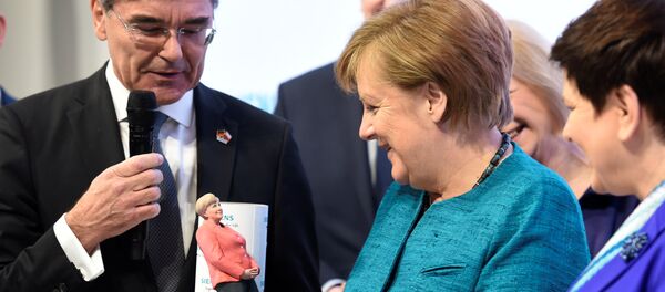 Angela Merkel elinde kendisinin üç boyutlu mini heykelini itutarken - Sputnik Türkiye