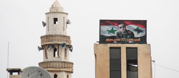 Hama'ya bağlı Suran kasabasında bir caminin yanında bulunan Suriye Devlet Başkanı Beşar Esad'ın fotoğrafının yer aldığı pano - Sputnik Türkiye