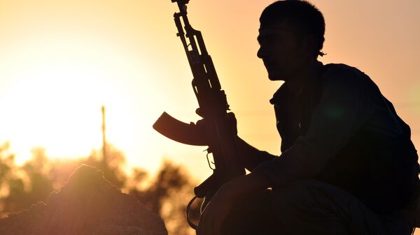 A fighter from the Kurdish People Protection Unit (YPG) poses for a photo at sunset in the Syrian town of Ain Issi, some 50 kilometres north of Raqqa, the self-proclaimed capital of the Islamic State (IS) group during clashes between IS group jihadists and YPG fighters on July 10, 2015 - Sputnik Türkiye