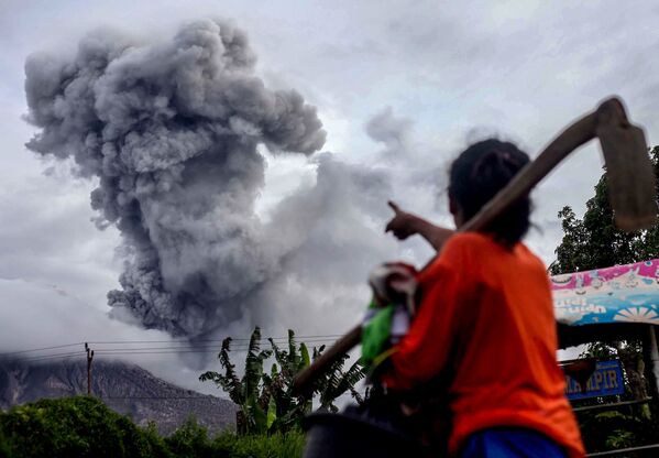 Köy sakinleri, yoğun kül püsküren Sinabung yanardağına işaret ediyor, Kuzey Sumatra. - Sputnik Türkiye