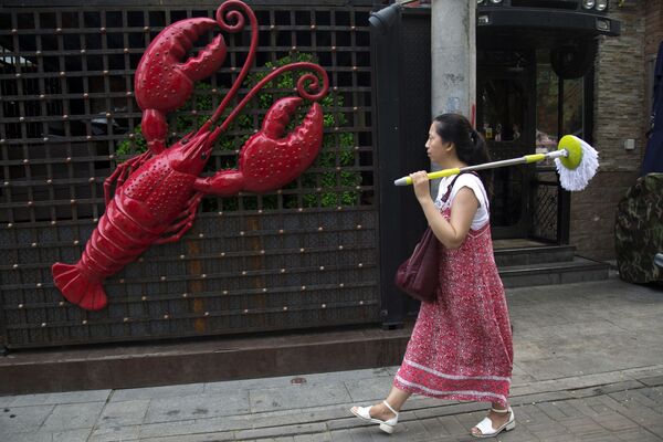 Pekin'de bir kadın, kerevit restoranının önünden geçerken. Sıkça acı ve baharatlı yenen kerevit Çin'de popüler bir yemektir. - Sputnik Türkiye