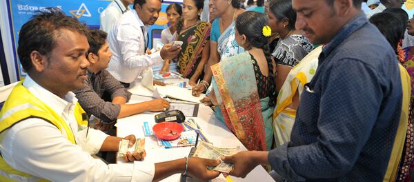 An Indian visitor (R) receives cash from a bank employee after withdrawing money from his bank account with his Aadhaar or Unique Identification (UID) card during a Digi Dhan Mela, held to promote digital payment, in Hyderabad on January 18, 2017 - Sputnik Türkiye