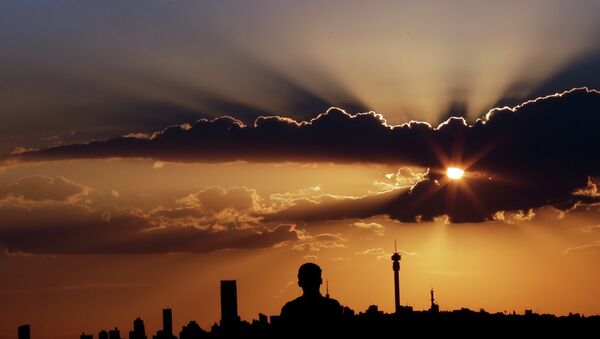 A man watches the sun set in as he overlooks the skyline in Johannesburg, South Africa - Sputnik Türkiye