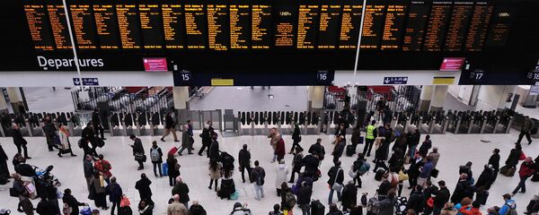 People wait with their luggage by the departure boards in Waterloo train station in central London - Sputnik Türkiye