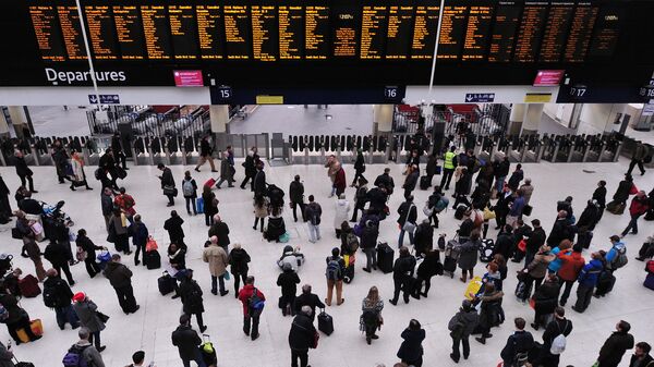 People wait with their luggage by the departure boards in Waterloo train station in central London - Sputnik Türkiye