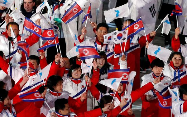 Kuzey Kore ve Güney Koreli sporcular ellerinde birleşik Kore, Kuzey Kore ve Güney Kore bayraklarıyla yine birlikte yürüdü. - Sputnik Türkiye