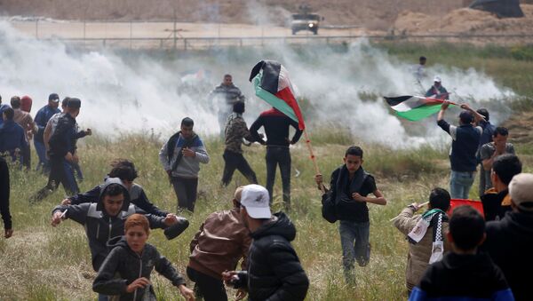 Palestinians run from tear gas fired by Israeli troops during clashes, during a tent city protest along the Israel border with Gaza, demanding the right to return to their homeland, east of Gaza - Sputnik Türkiye