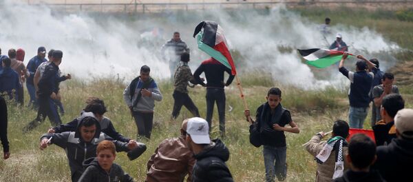 Palestinians run from tear gas fired by Israeli troops during clashes, during a tent city protest along the Israel border with Gaza, demanding the right to return to their homeland, east of Gaza - Sputnik Türkiye