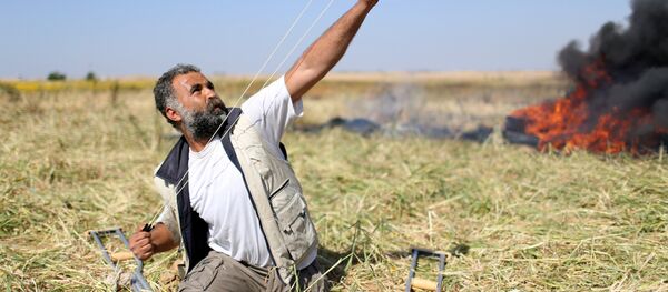 Gazze'de 'Toprak Günü' nedeniyle yapılan gösterilerde sınırdaki İsrail askerlerine taş atan bir Filistinli - Sputnik Türkiye