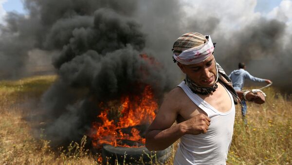A Palestinian runs during clashes with Israeli troops, during a tent city protest along the Israel border with Gaza, demanding the right to return to their homeland, the southern Gaza Strip - Sputnik Türkiye