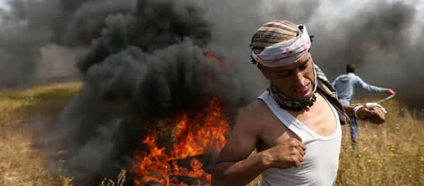 A Palestinian runs during clashes with Israeli troops, during a tent city protest along the Israel border with Gaza, demanding the right to return to their homeland, the southern Gaza Strip A Palestinian runs during clashes with Israeli troops, during a tent city protest along the Israel border with Gaza, demanding the right to return to their homeland, the southern Gaza Strip - Sputnik Türkiye