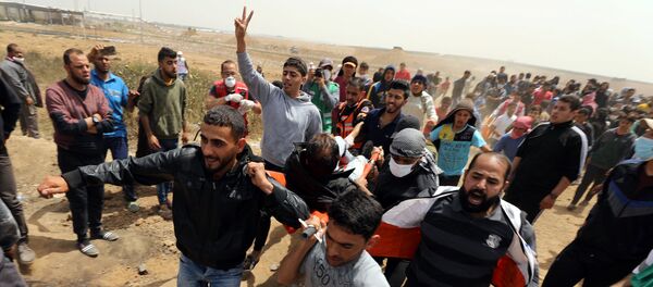 A wounded Palestinian is evacuated during clashes with Israeli troops at a protest demanding the right to return to their homeland, at the Israel-Gaza border, east of Gaza City, April 13, 2018 - Sputnik Türkiye