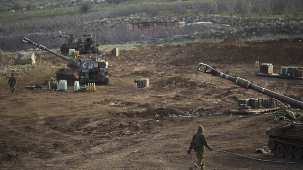 Israeli soldiers walk next to mobile artillery units in the Israeli-occupied Golan Heights near the border with Syria. (File) - Sputnik Türkiye