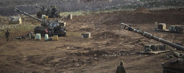 Israeli soldiers walk next to mobile artillery units in the Israeli-occupied Golan Heights near the border with Syria. (File) - Sputnik Türkiye