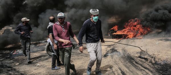 Palestinian protesters pull on a burning tire during clashes with Israeli forces on April 20, 2018, east of Khan Yunis, in the southern Gaza Strip during mass protests along the border of the Palestinian enclave, dubbed The Great March of Return, which has the backing of Gaza's Islamist rulers Hamas - Sputnik Türkiye